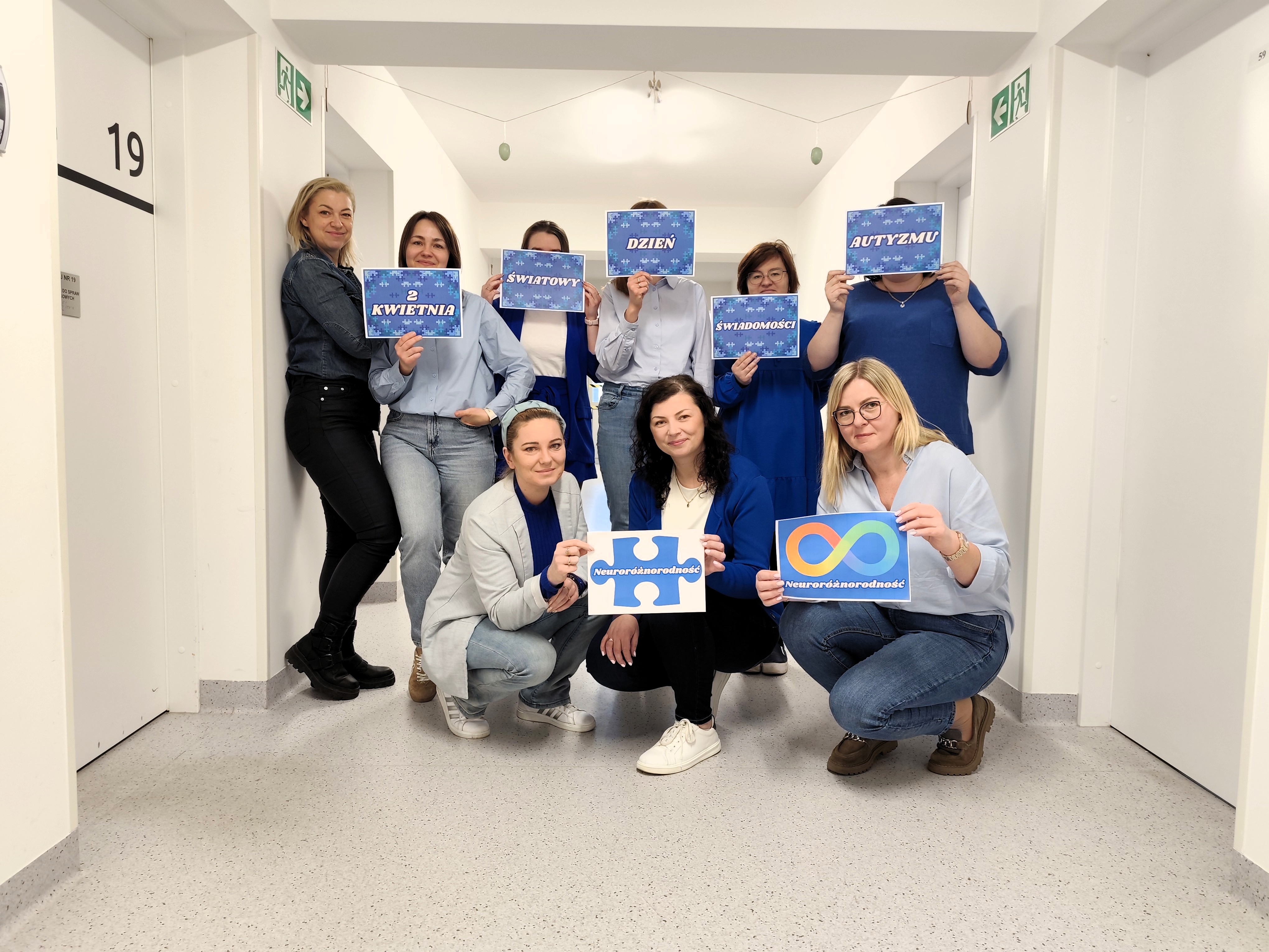Zdjęcie: pracownicy w dw&oacute;ch rzędach na korytarzu, każdy ubrany na niebiesko lub z niebieskim akecenten. Dziś światowy dzień świadomości  autyzmu.