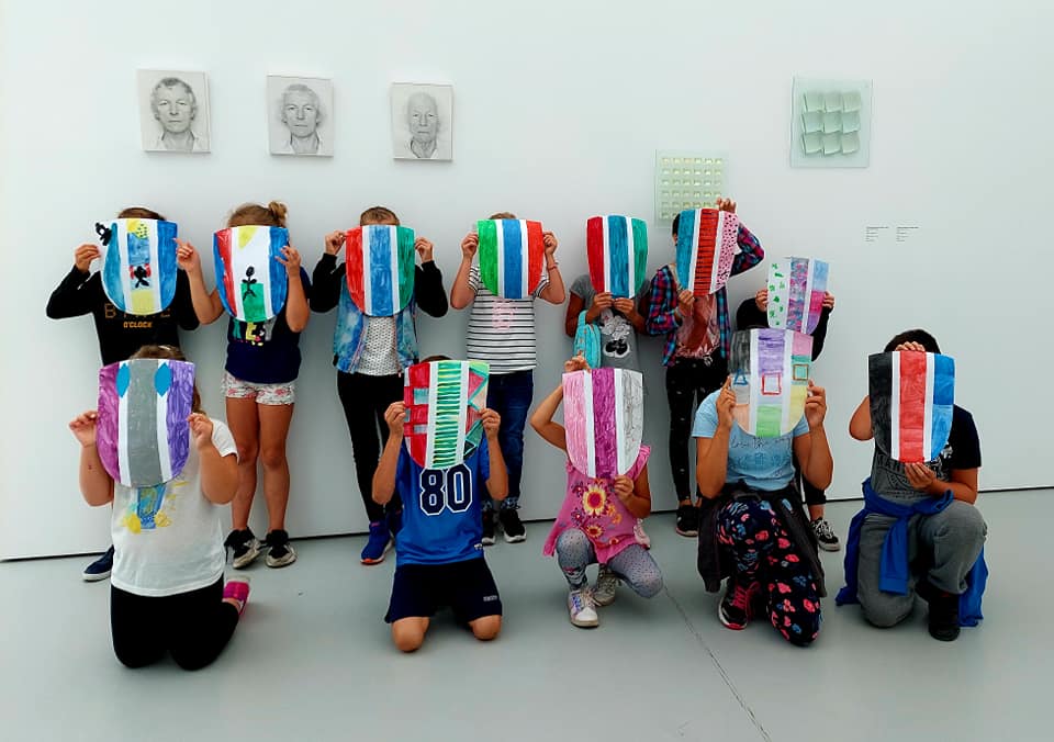 zdjęcie: grupa dzieci ustawiona do zdjęcia, zasłaniają twarze kolorowymi maskami